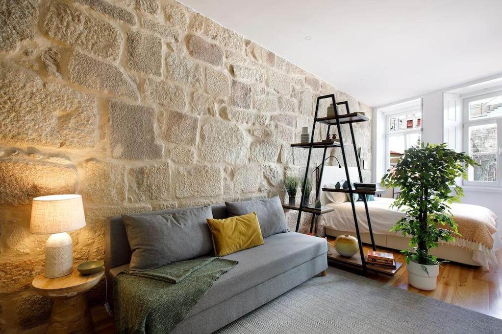 sala de estar con sofá y pared de piedra en Oporto Lovely Apartment, en Oporto