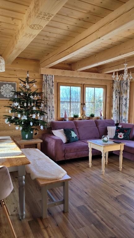 - un salon avec un canapé violet et un arbre de Noël dans l'établissement Górskie Przysiółki w Koniakowie - Dom z bala KORONKA, à Koniaków