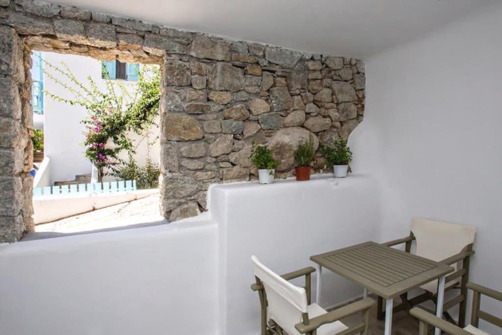 una mesa y sillas frente a una pared de piedra en Raffar luxury houses Psarou en Platis Yialos Mykonos