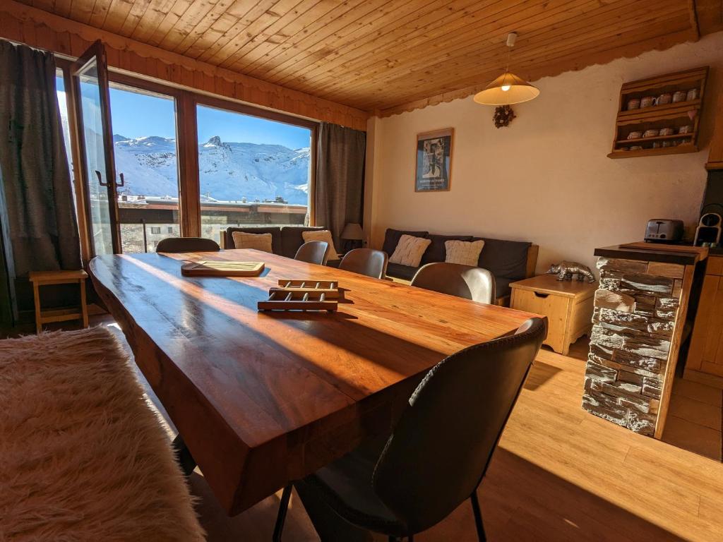 a large wooden table in a living room with mountains at Appartement au lac ski aux pieds in Tignes