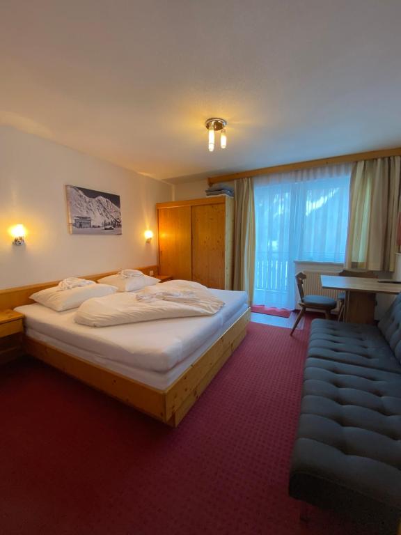 a hotel room with a large bed and a couch at Bella Mira in Samnaun - Laret
