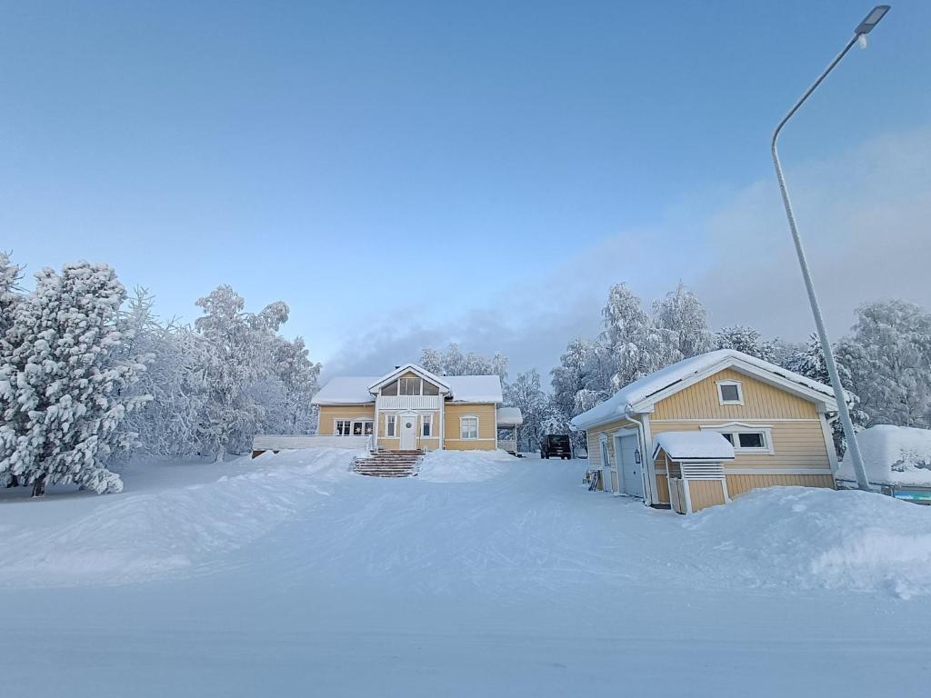 a house is covered in snow with trees at Arctic Lakeside Home in Kemijärvi