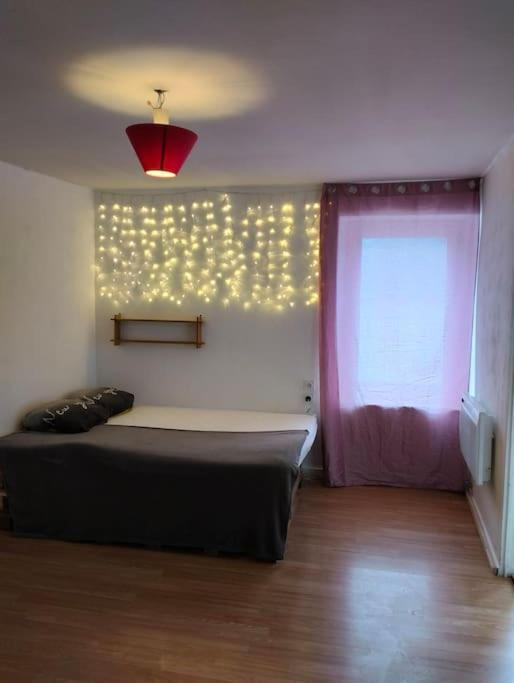 een slaapkamer met een bed en een raam met verlichting bij Appartement cosy et chaleureux in Morez
