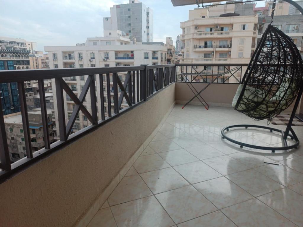 a chair on a balcony with a view of a city at Luxury apartment in laurent in Alexandria