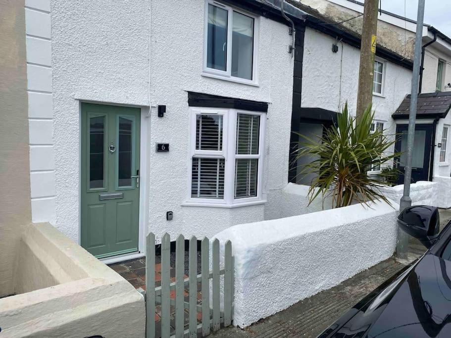 een wit huis met een groene deur en een hek bij Roselea Cottage in Llangadwaladr