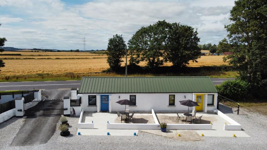 a white building with a green roof with tables and umbrellas at The Roadshed Apartments @ Rohans Farm in Midleton