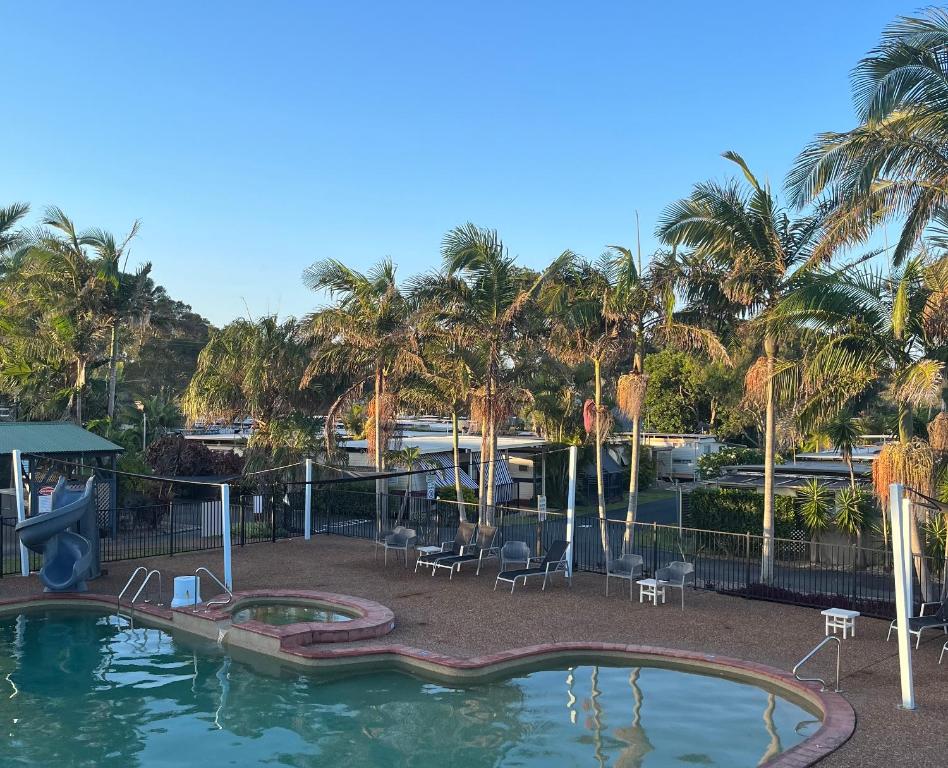 una piscina con sedie e uno scivolo in un resort di Diamond Beach Holiday Park a Diamond Beach