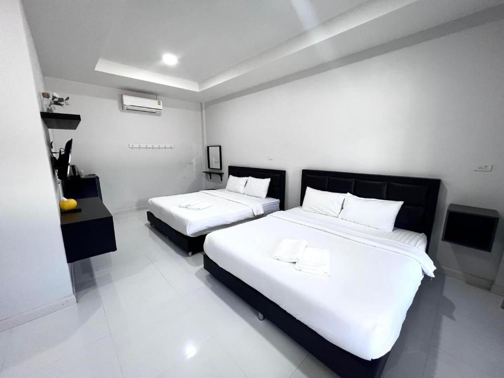 1 dormitorio con 2 camas con sábanas blancas en บารอนรีสอร์ทสระแก้ว en Sa Kaeo