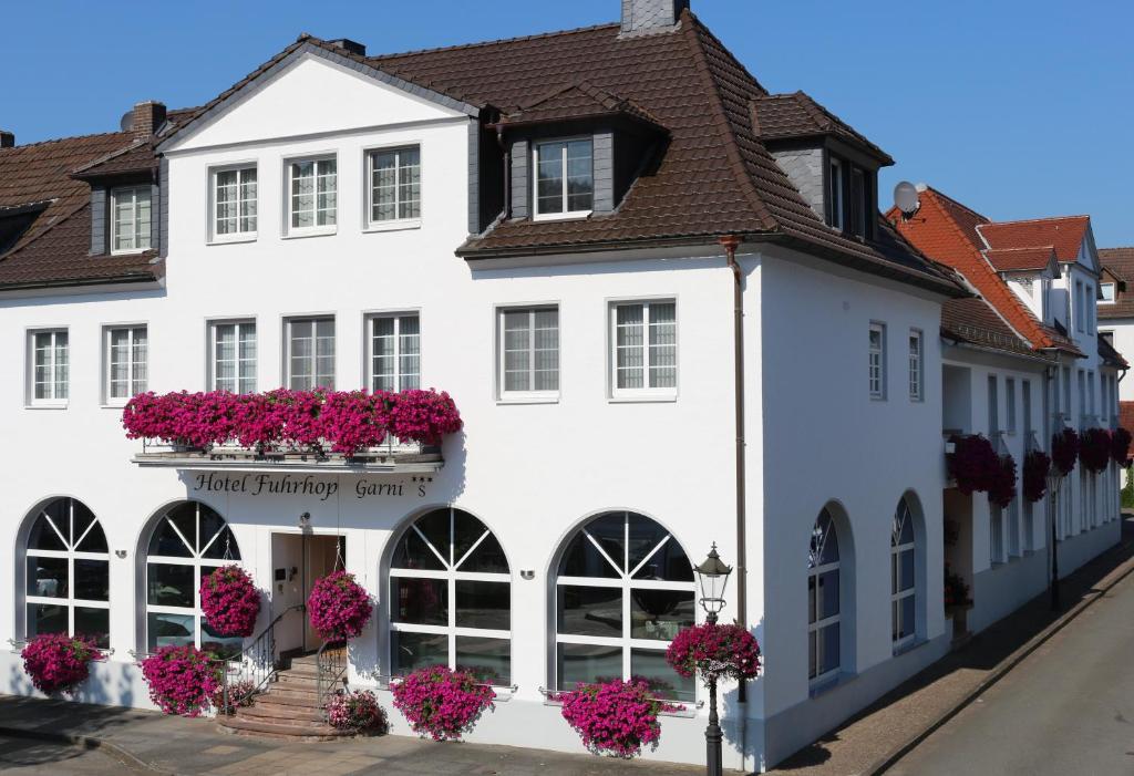 ein weißes Gebäude mit Blumen an den Fenstern in der Unterkunft Hotel Garni Fuhrhop in Bad Karlshafen