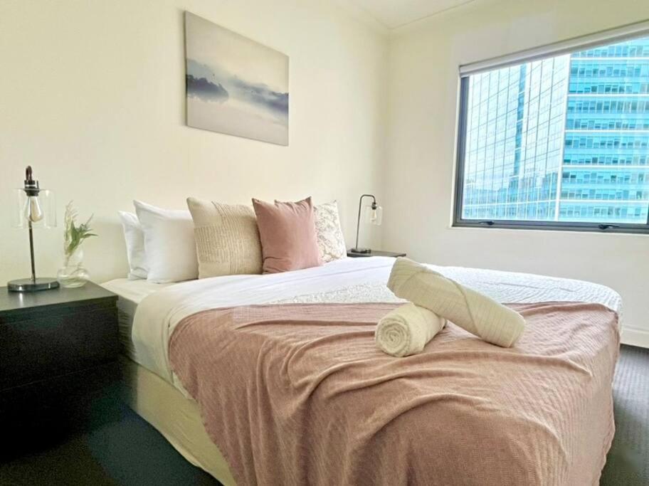 1 dormitorio con 1 cama grande y ventana en A Cozy 2B2B Apt Next To Carlton Garden W/ Parking, en Melbourne