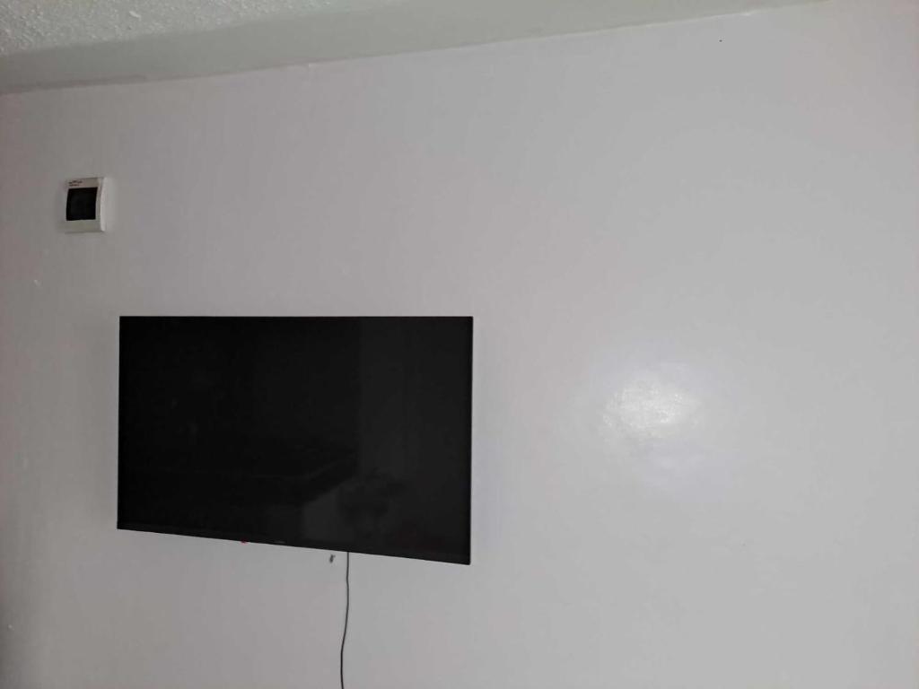 einen Flachbild-TV, der an einer weißen Wand hängt in der Unterkunft Cottage 1 in Nairobi