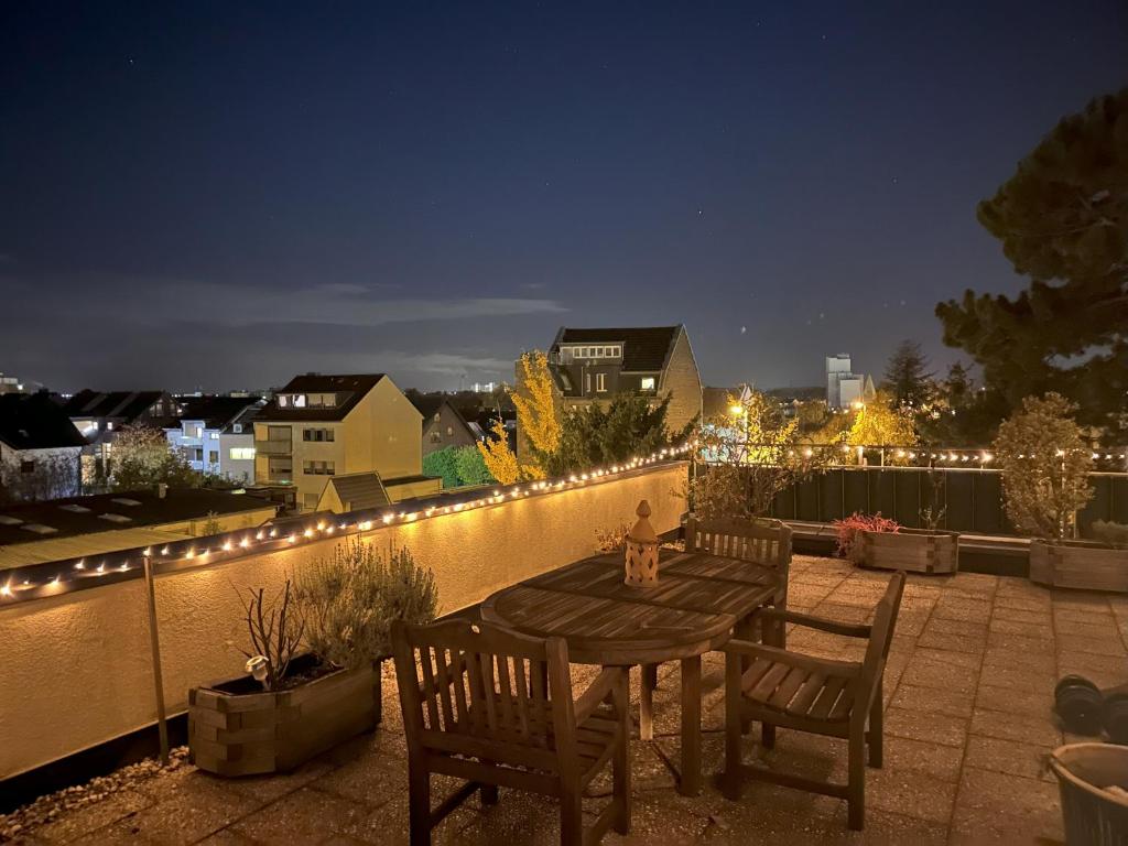 a wooden table and chairs on a patio at night at Village Vista Penthouse in Wesseling