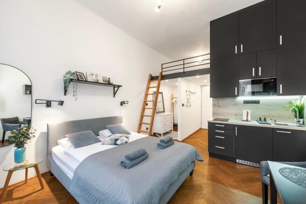 a bedroom with a bed and a kitchen with a ladder at Awesome Stay Studios in Prague