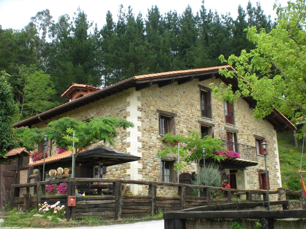 una casa de piedra con una valla de madera delante de ella en Agroturismo Iturbe, en Axpe de Busturia