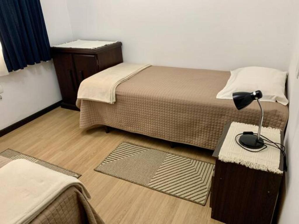 a bedroom with two beds and a lamp on a table at Casa Leicht - Quarto Solteiro in Blumenau