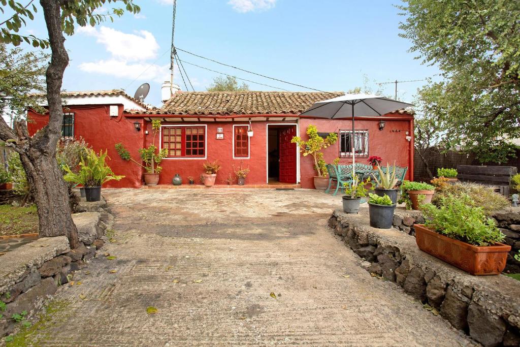a red house with an umbrella in front of it at Casa Rural La Asomada in Vega de San Mateo