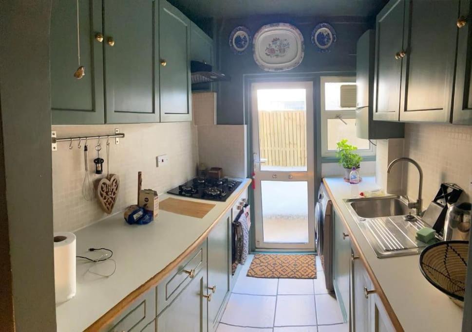 a small kitchen with green cabinets and a sink at Kensal Green - Garden Retreat in London