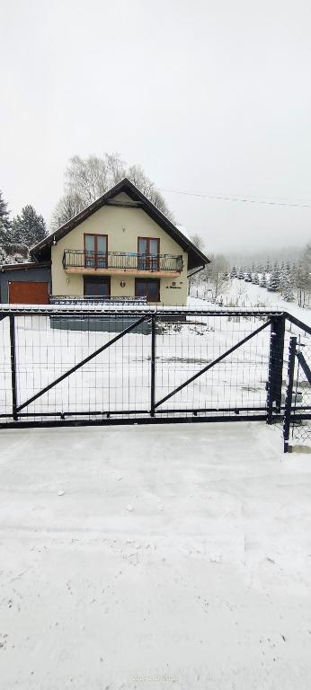 a house with a gate in the snow at Pokoje na Widokowej 33 in Korbielów