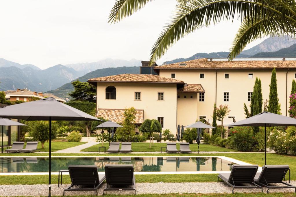 a villa with a swimming pool with chairs and umbrellas at Monastero Arx Vivendi in Arco