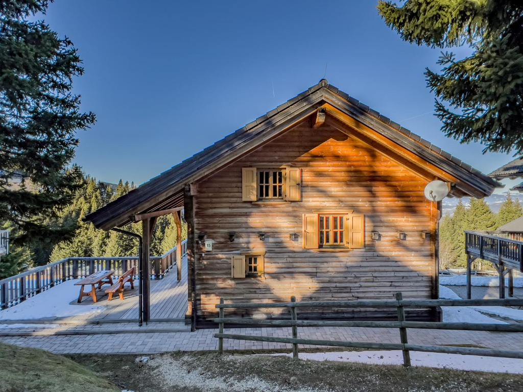 ein Blockhaus mit einer Veranda im Schnee in der Unterkunft 1A Chalet Koralpenzauber - Wandern, Sauna, Grillen mit Traumblick in Wolfsberg