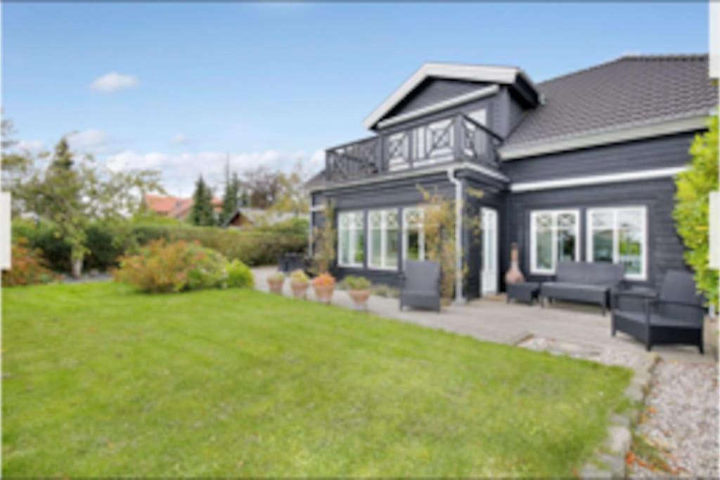 a black house with a lawn in front of it at Eksklusivt hus på 250 m2 i naturskønne omgivelser in Hørsholm