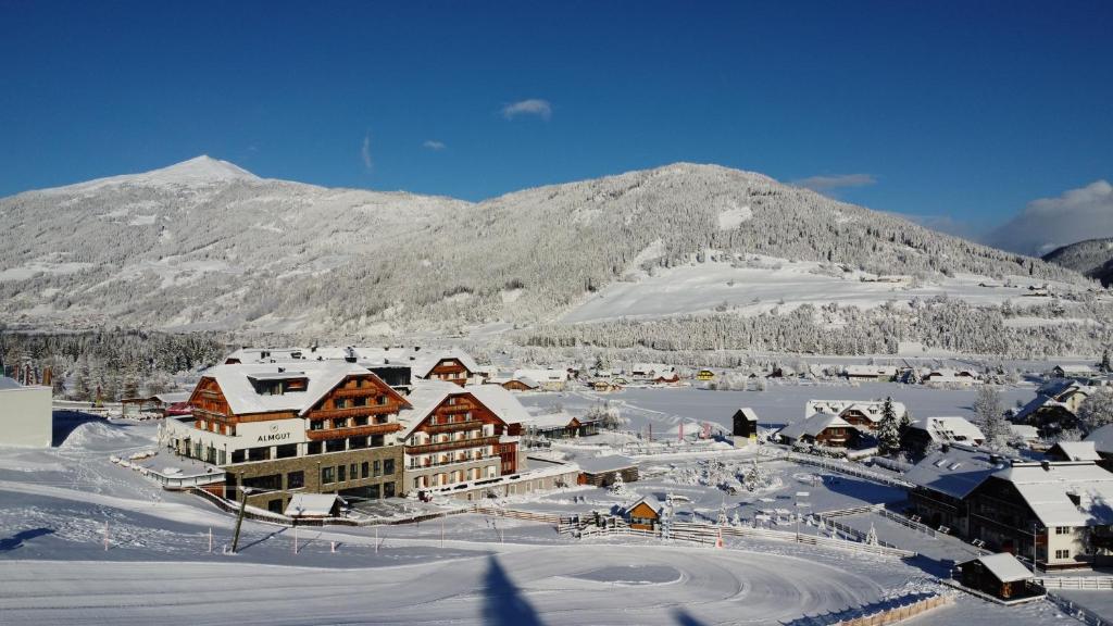 a town in the snow in front of a mountain at ALMGUT - Mountain Wellness Hotel in Sankt Margarethen im Lungau
