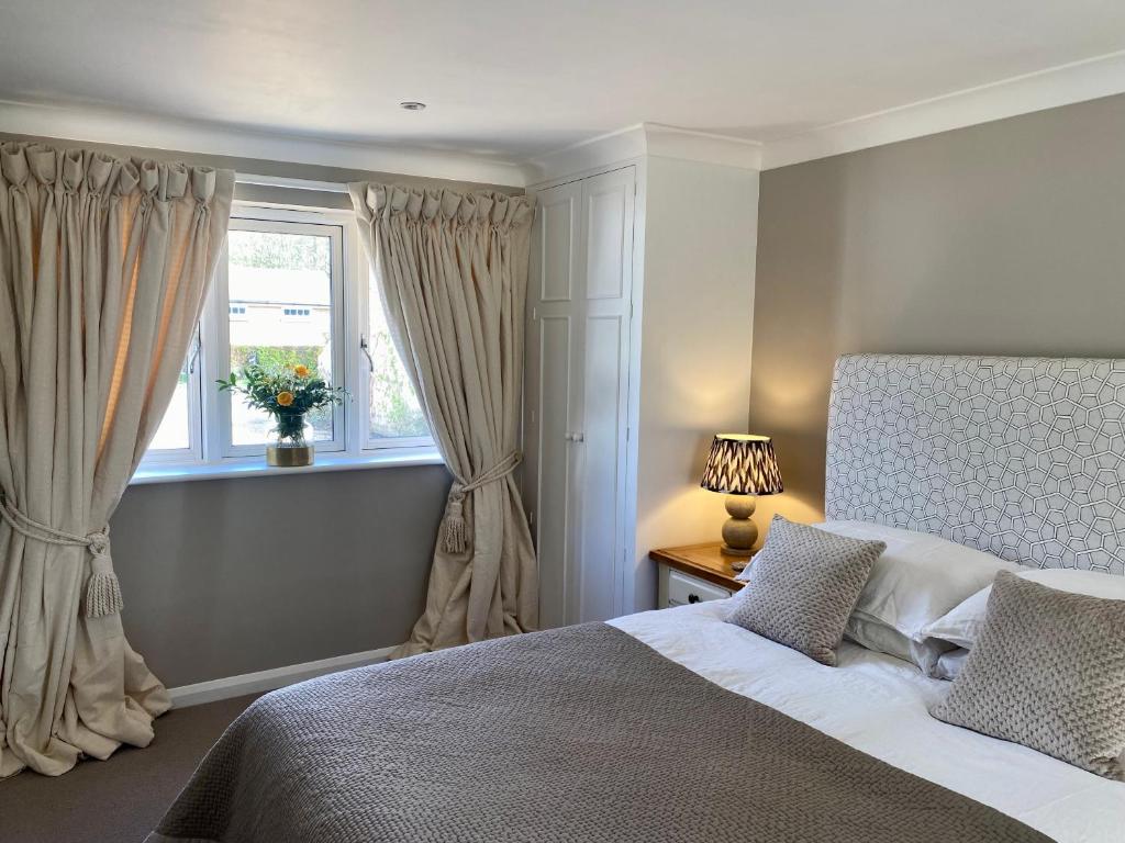a bedroom with a large bed and a window at Beautifully appointed one-bedroom cottage in Shepreth