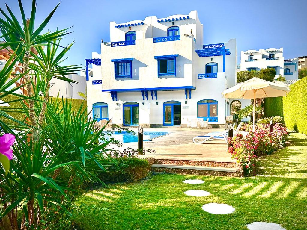 a white house with blue windows and a yard at Luxury Villa with pool in Hurghada in Hurghada