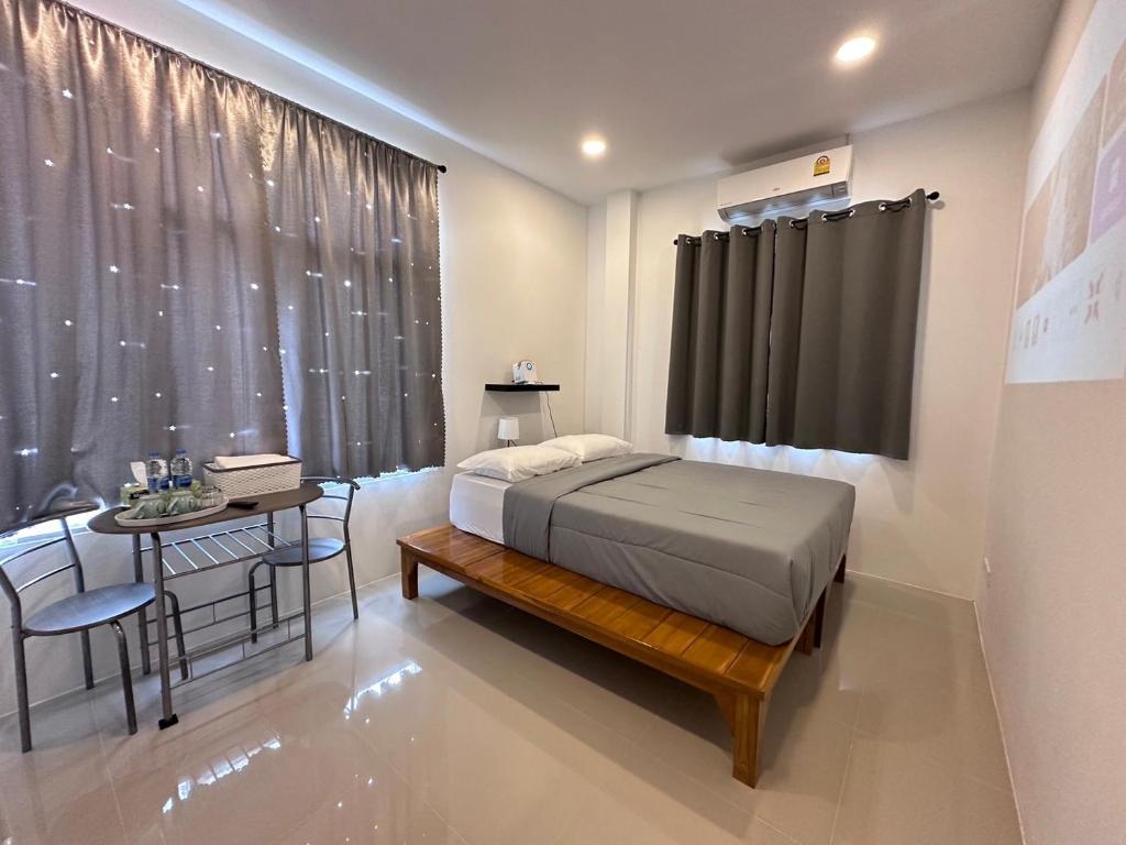 a bedroom with a bed and a table and a window at Janis Home in Ban Noi Pho Kham