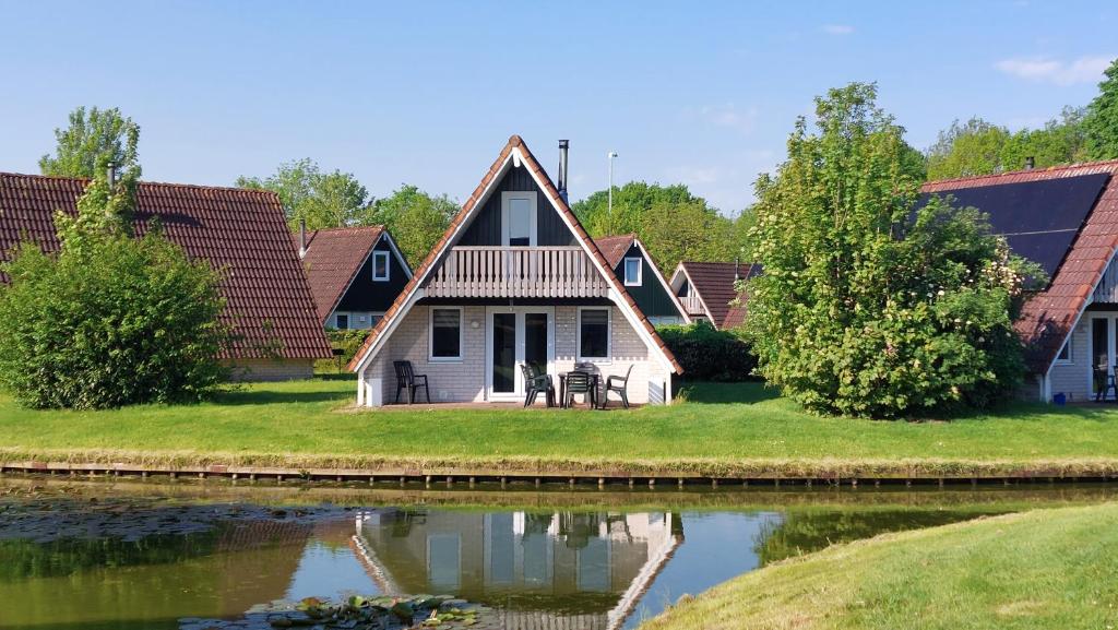 une maison avec un étang en face de celle-ci dans l'établissement Luxe 6-persoons vakantiewoning Gramsbergs Huuske, à Gramsbergen