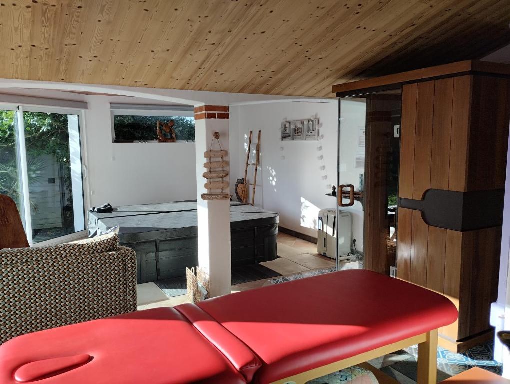 a living room with a red bench and a bed at L'eden naturiste spas in Challans