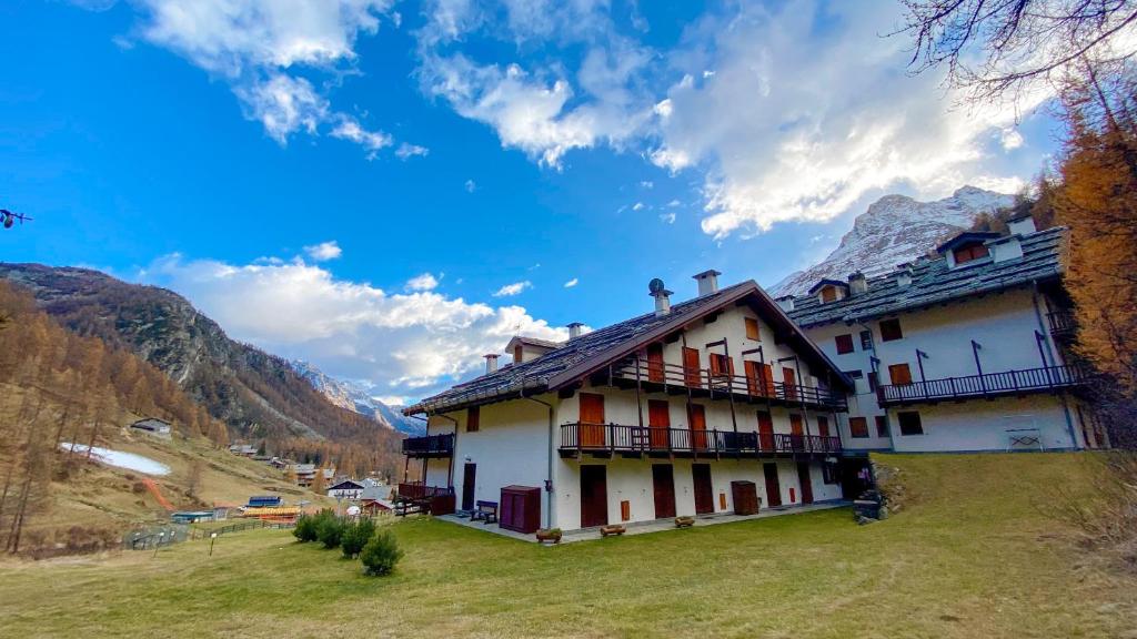 a building on a hill with mountains in the background at Lys Apartment in Gressoney-la-Trinité