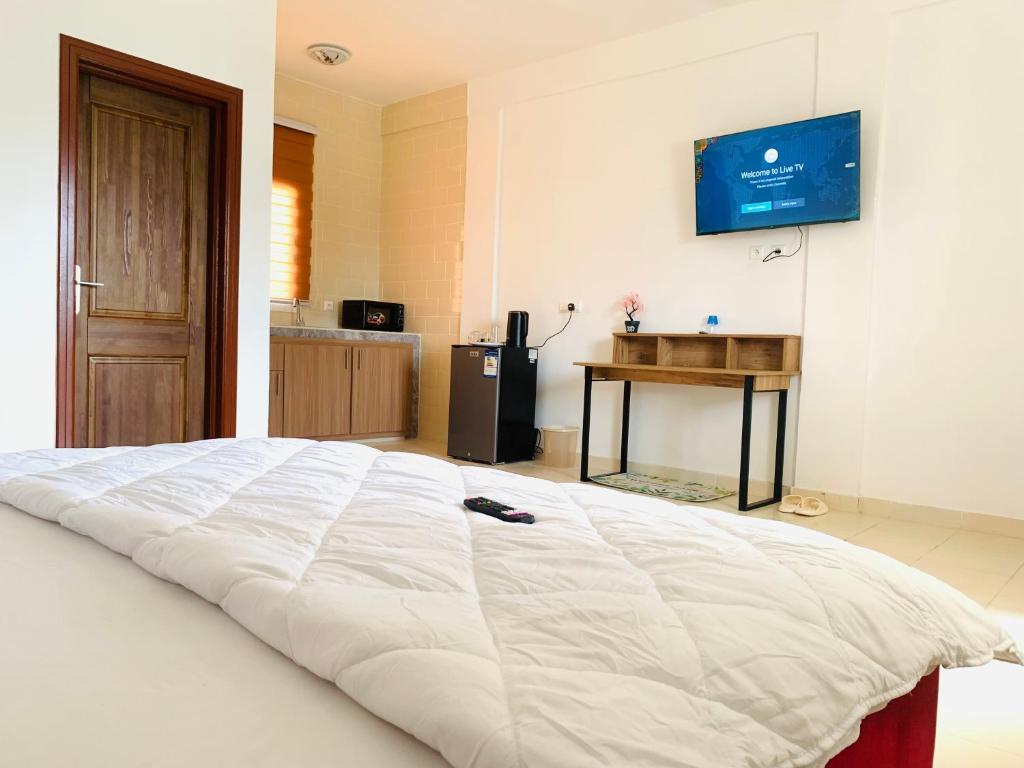 a bedroom with a large white bed with a television on the wall at Namaste hotel & restaurant in Libreville