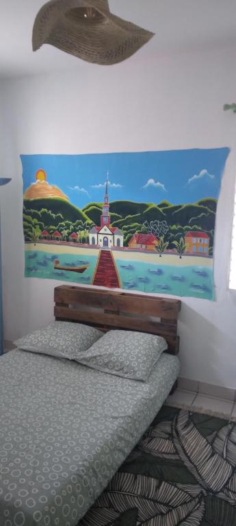 a bedroom with a bed with a painting on the wall at Chambre d'hôtes pieds dans l'eau in Grande Anse