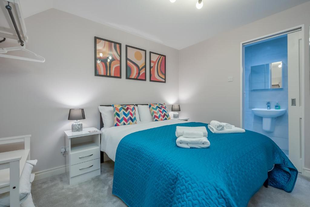 a white bedroom with a blue bed and a sink at Belfast City Centre - 3 bed, 3 bathroom & parking by StayByNumbers in Belfast
