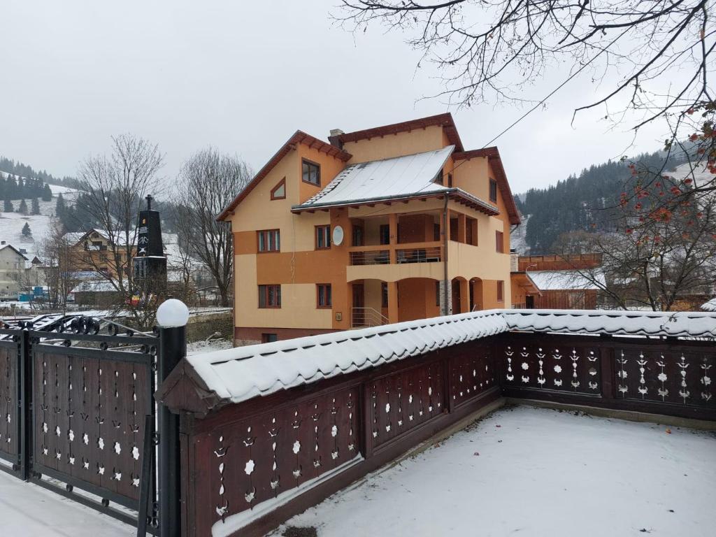 une maison avec une clôture recouverte de neige devant elle dans l'établissement Pensiunea Adela, à Fundu Moldovei