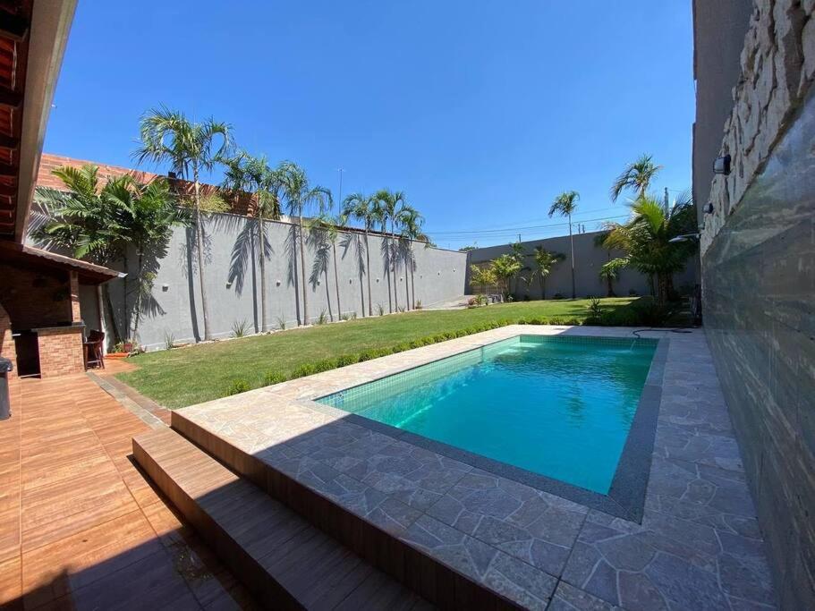 uma piscina com um banco ao lado de uma casa em Casa Sa Pedra em Aparecida de Goiânia