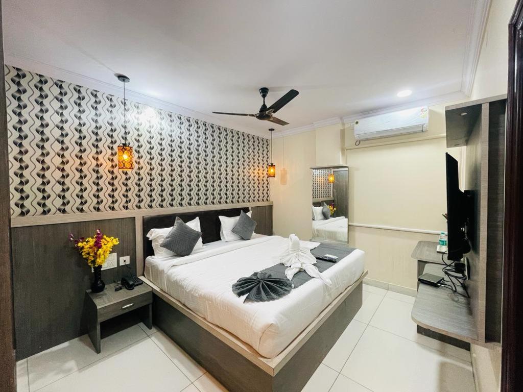 a bedroom with a large bed and a bathroom at Hotel Blue Petals in Shamshabad