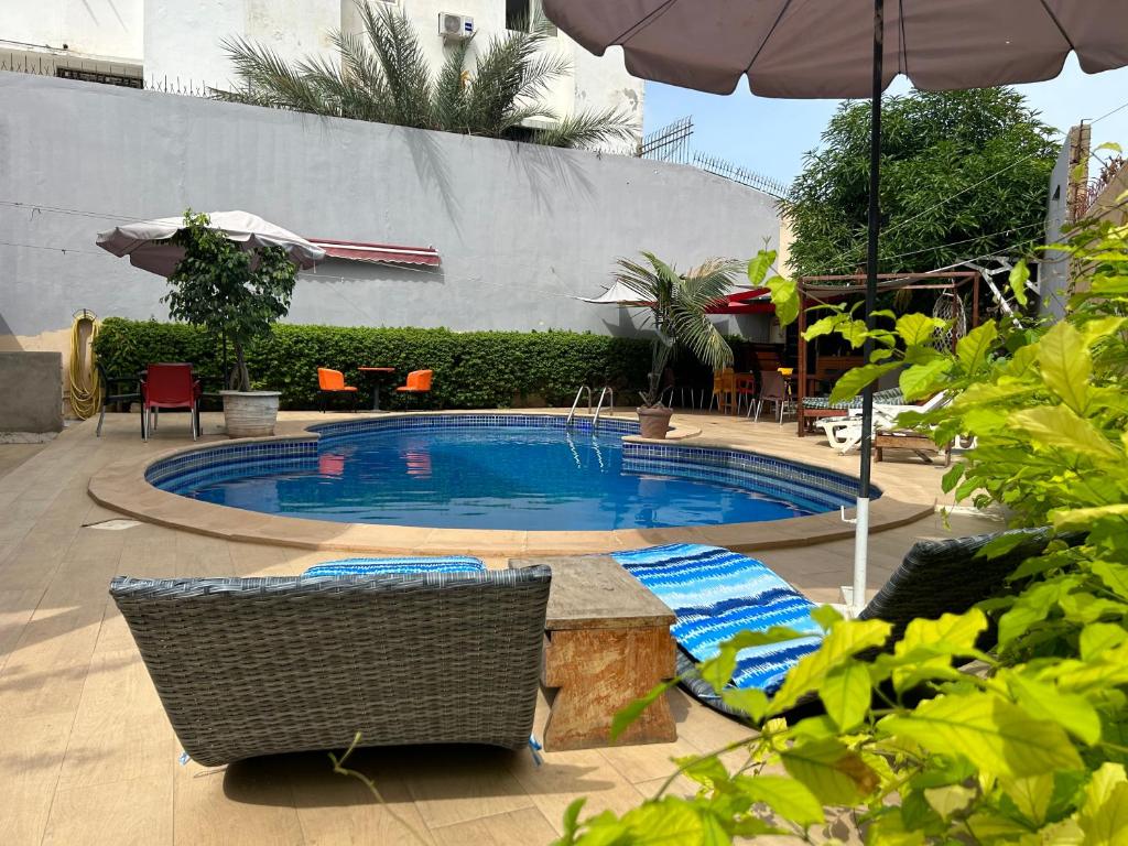 a swimming pool with chairs and an umbrella at Villa Jade in Dakar