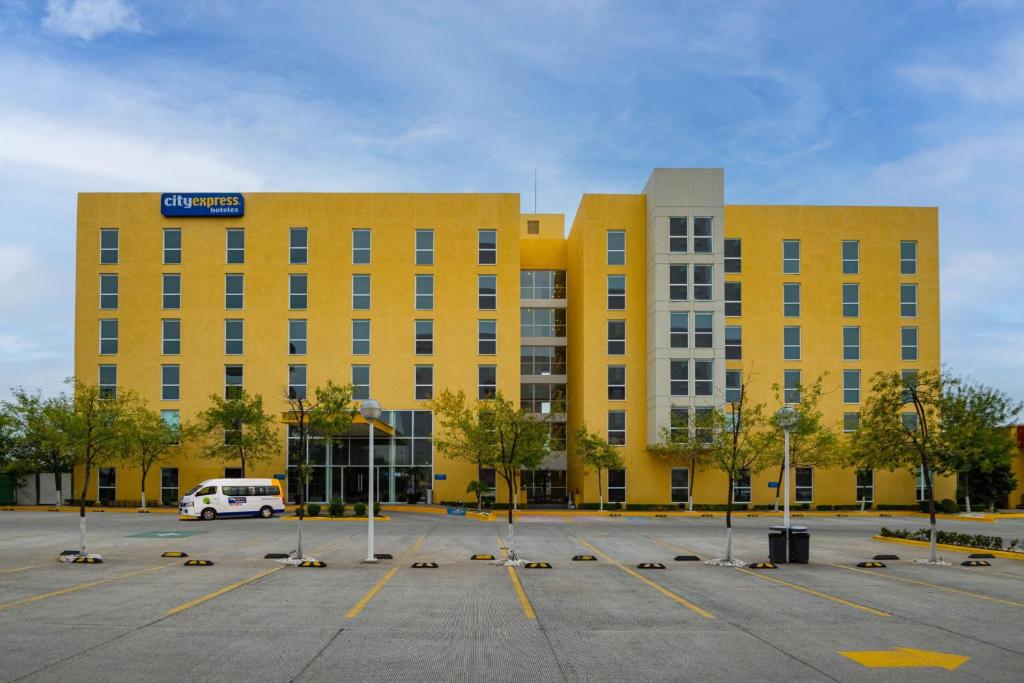 um edifício amarelo com um parque de estacionamento em frente em City Express by Marriott Silao Aeropuerto em Silao