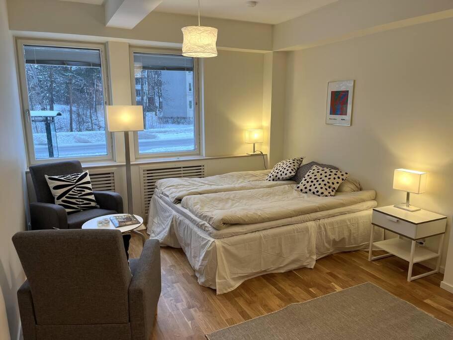 ein Schlafzimmer mit einem Bett und einem Stuhl sowie zwei Fenstern in der Unterkunft New apartment, perfect for exploring Stockholm in Lidingö