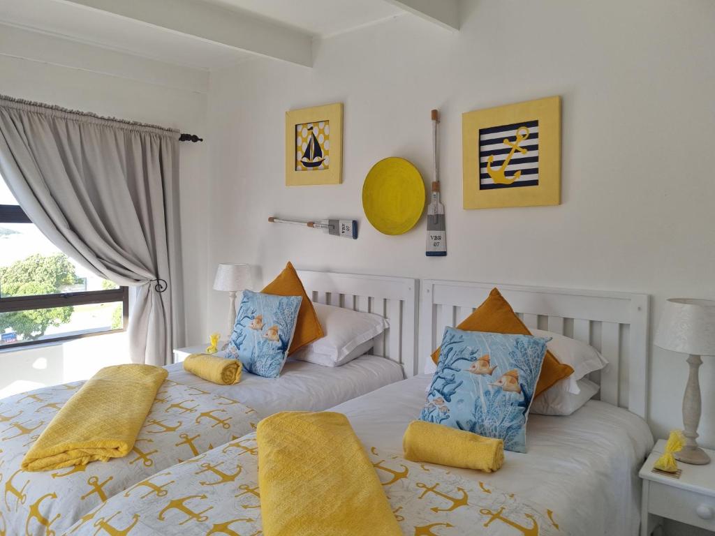 a bedroom with two beds with yellow and blue pillows at South Of Africa in Agulhas