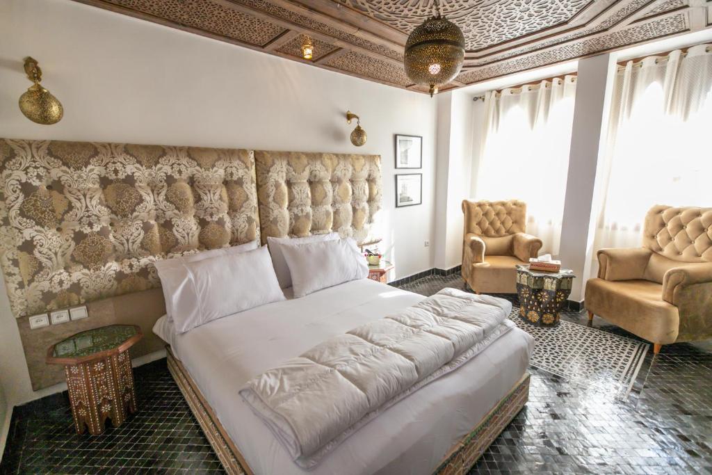 a bedroom with a large bed and two chairs at Darif's Riad Fes & Spa in Fez