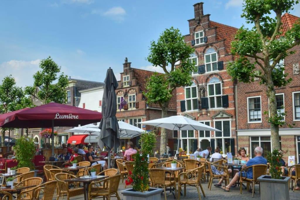 una cafetería al aire libre con mesas, sillas y edificios en De Kapelle in Oudewater, en Oudewater