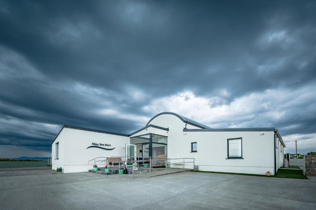 a white building with a cloudy sky behind it at Sligo Sea Barn in Sligo