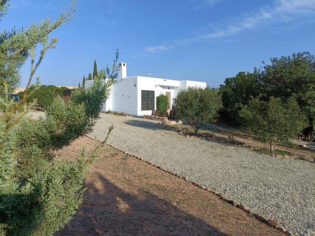 una pequeña casa blanca con entrada de grava en El Cerrillo, en Agua Amarga