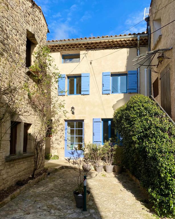 un bâtiment avec des fenêtres et des plantes à volets bleus dans l'établissement Charmante maison de village au coeur du Luberon, à Cucuron