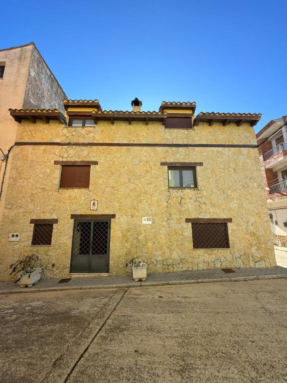 un edificio de ladrillo amarillo con ventanas y una puerta en Casa rural María Juliana en Talayuelas