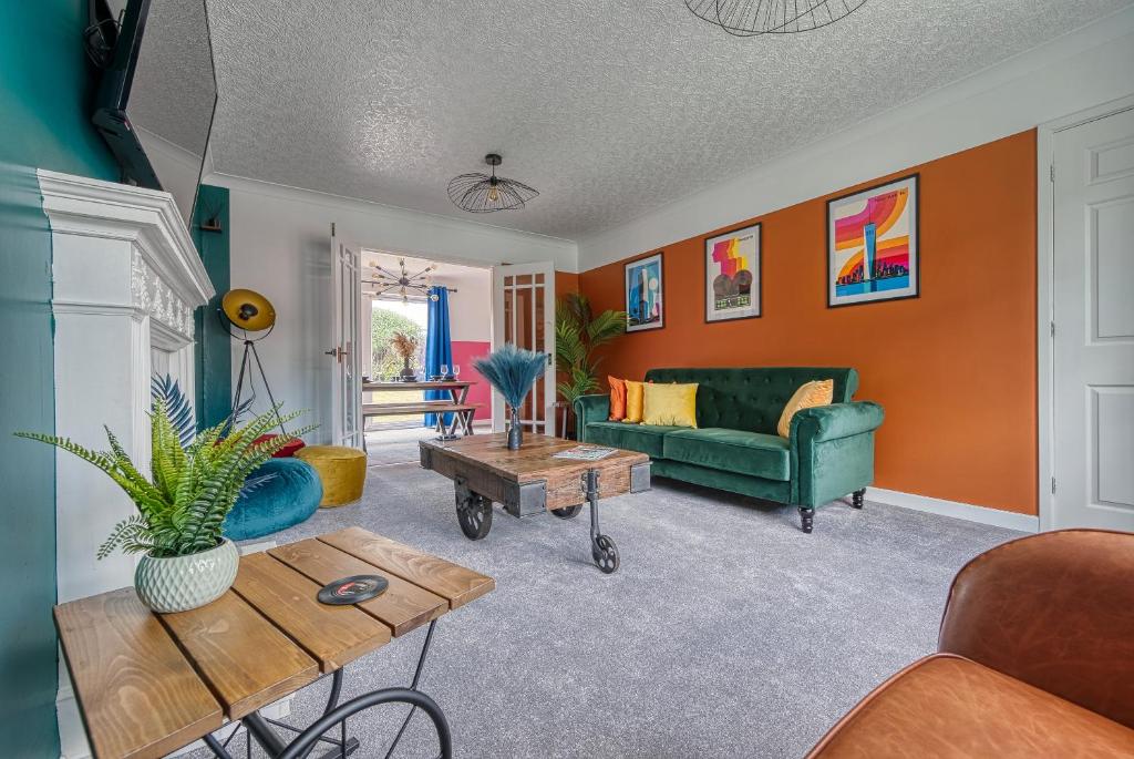 uma sala de estar com paredes cor de laranja e um sofá verde em Large 4 bedroom house - driveway - close to NEC! em Solihull
