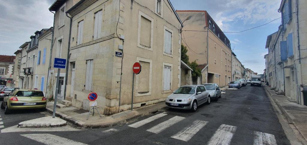 une rue avec des voitures garées sur le côté d'un bâtiment dans l'établissement Maison de centre ville, à Périgueux